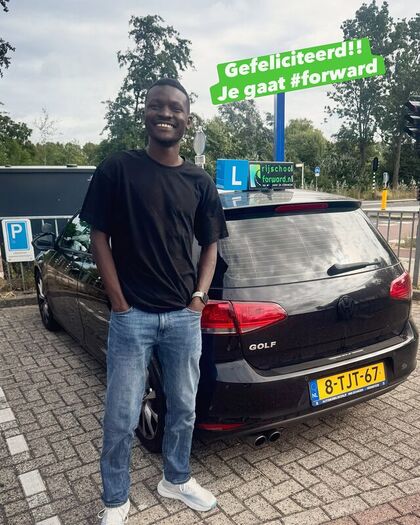 Geslaagde leerling bij de achterklep van de lesauto