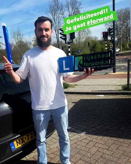 Geslaagde leerling met het blauwe L-bord in de hand